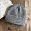 Dettaglio del berretto in maglia grigia a costine su scrivania in legno e rivista - M / grigio scuro