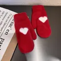 Close-up of soft red plush mittens with a white heart pattern on a dark metal surface - One Size / Red