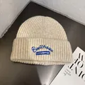 Close-up of ribbed knit texture on a beige beanie with blue embroidered logo and lettering - M (55-59cm) / Beige