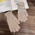Detailed texture of beige knitted gloves with decorative green wavy borders on wood surface - Beige