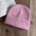 Dettaglio ravvicinato del berretto in maglia a coste rosa con risvolto su sfondo in legno - M / Rosa
