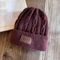 Detail of chunky knit dark purple beanie with City no city leather patch on wooden desk - M (55-59cm) / Burgundy