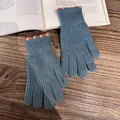 Close-up of blue knitted gloves with orange dot cuffs on a rustic wooden table - Peacock Blue