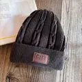 Detail of dark grey thick knit beanie with retro CITY leather patch on wooden surface - M (55-59cm) / Coffee