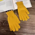 Detail of yellow knit gloves with colorful wavy cuffs on a wooden table with an open book - Yellow