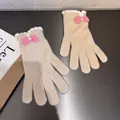 Dettaglio di guanti in maglia con fiocco rosa felpato, perla e bordi ondulati bianchi - Beige