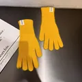Details von ingwergelben Kaninchenfell-Strickhandschuhen mit Handmade-Label auf schwarzem Tisch - Einheitsgröße / Gelb