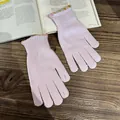 Close-up of pink knit gloves with decorative scalloped edges on a rustic book - Lavender