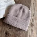 Primo piano del berretto in maglia a coste viola su un tavolo di legno con un libro - M / Caffè Chiaro