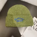 Detail view of grass green knitted beanie with blue letter embroidery and ribbed texture - M (55-59cm) / Green