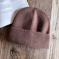 Texture détaillée d'un bonnet en tricot marron café épais sur un fond en bois rustique - M / Café