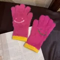 Détail de gants en peluche rose avec motif smiley et poignets contrastés en tricot jaune vif - Taille unique / Rose rouge