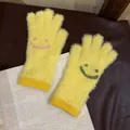 Details von gelben Plüschhandschuhen mit Strick-Smileys auf einem Zeitungshintergrund - Einheitsgröße / Gelb