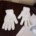 Close-up of soft white plush coral fleece gloves with elastic cuffs on a dark leather surface - Adult / White
