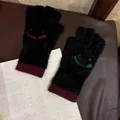 Detail von schwarzen Plüsch-Strickhandschuhen mit bunten Smileys auf Vintage-Papierhintergrund - Einheitsgröße / Schwarz