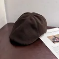 Detailed texture of dark brown wool felt flat cap placed on a rustic wooden table - M / Coffee