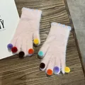Detail von rosa Pelzhandschuhen mit bunten Bommeln auf einem rustikalen Holzhintergrund - Einheitsgröße / Rosa