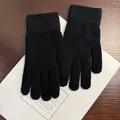 Detailaufnahme schwarzer Strickhandschuhe mit langen Rippbündchen auf Holzgrund - Einheitsgröße / Schwarz