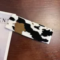 Detailed close-up of the knitted cow pattern headband with soft texture on wood surface - Big Spotted Cow