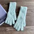 Detail von hellgrünen Webpelz-Handschuhen mit Rippbündchen auf dunklem Holz - Mintgrün