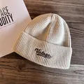 Macro shot of beige ribbed knit beanie featuring vintage brown embroidery on dark wood - M (55-59cm) / Beige