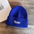 Close-up of royal blue knitted beanie with white Vintage embroidery on wooden background - M (55-59cm) / Royal Blue