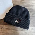 Dettaglio ravvicinato di un berretto in maglia nera con ricamo bianco di cucciolo lucky - M (55-59cm) / Nero