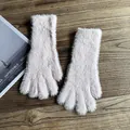 Nahaufnahme weicher rosa Pelzhandschuhe auf Holztisch mit dekorativem Magazin im Hintergrund - Hellrosa