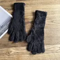 Detailaufnahme schwarzer Strickhandschuhe aus Plüsch auf einem Holzgrund - Schwarz