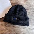 Close-up of black ribbed knit beanie featuring colorful dachshund dog embroidery on the cuff - M (55-59cm) / Black