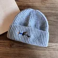 Detail of light blue ribbed knit beanie with embroidered dachshund on wood table - M (55-59cm) / Blue