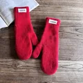 Macro shot of red knit mittens with fluffy mohair texture and a white fashion label - One Size / Red