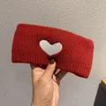 Close-up of a wide red knitted headband featuring a white heart pattern in winter wool - Red