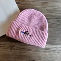 Detailed view of pink ribbed knit beanie with cute puppy embroidery on a wooden surface - M (55-59cm) / Pink