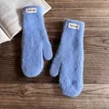 Detail of light blue fluffy knit mittens with fashion label on a wooden desk - One Size / Blue