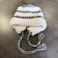 Detail of plush earflap hat with blue knit wave pattern and braided tassel strings - M (55-59cm) / White