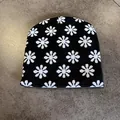 Macro view of black knit beanie featuring white floral patterns and textured embroidery - Black & White