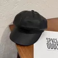 Detalle de gorra de cuero PU negro con grano texturizado sobre una mesa de madera - M / Negro