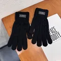 Primer plano de guantes de punto negros con etiqueta Classic sobre escritorio y revista - Negro