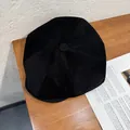Detail of black corduroy newsboy hat texture on a wooden table with a magazine - M (55-58cm) / Black
