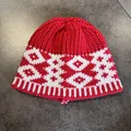 Close-up of thick red knit beanie with white geometric jacquard pattern and ribbed hem - Red