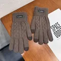Detalle de guantes de punto táctiles con etiqueta de cuero sobre escritorio de madera - Caqui