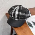 Detail einer Vintage-Schirmmütze aus Wollkaro mit schwarzem Leder-Schirm auf Holz - M / Schwarz Kariert
