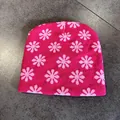 Flat lay detail of pink knitted beanie with light pink flower patterns on stone floor - Rose Pink