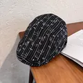 Dettaglio di una coppola a righe nere con ricamo a forma di piccolo cane bassotto - M / Nero