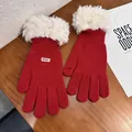 Detailed macro view of red knit gloves with white faux fur cuffs and touch screen fingertips - Red