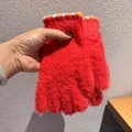 Detail von roten Plüschhandschuhen mit flauschiger Textur und gestreiften Bündchen für den Winter - Rot