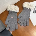Detail of grey knitted touchscreen gloves with white plush cuffs and pink logo label - Gray