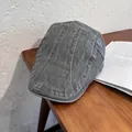 Dettaglio della coppola vintage in denim grigio lavato su scrivania in legno con libri - M (55-59cm) / Grigio