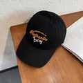 Détail de la broderie chien de dessin animé et texte orange sur casquette en coton noir - Réglable / Noir
